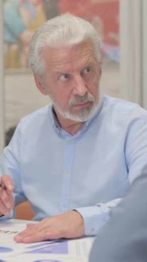 Senior Man Discussing Charts With Young Adult Woman