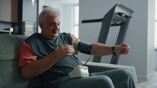 Man Measures Blood Pressure at Home on Couch