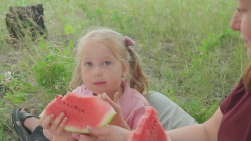 Young Girl Savoring Fresh Watermelon in Field Atmosphere Girl with Braided Hair Delicately Tasting