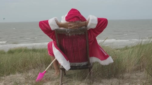 santa claus alone on holiday enjoy the silence and the breeze sitting on a deckchair or beach lounge