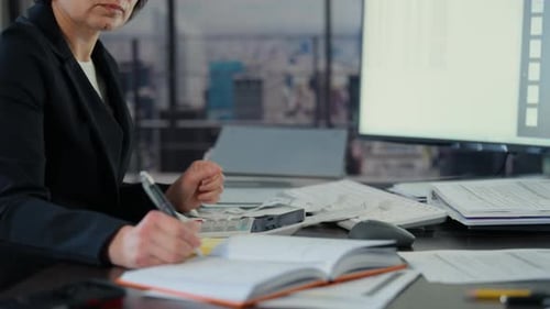 Woman Calculates Finances at Desk in City Office