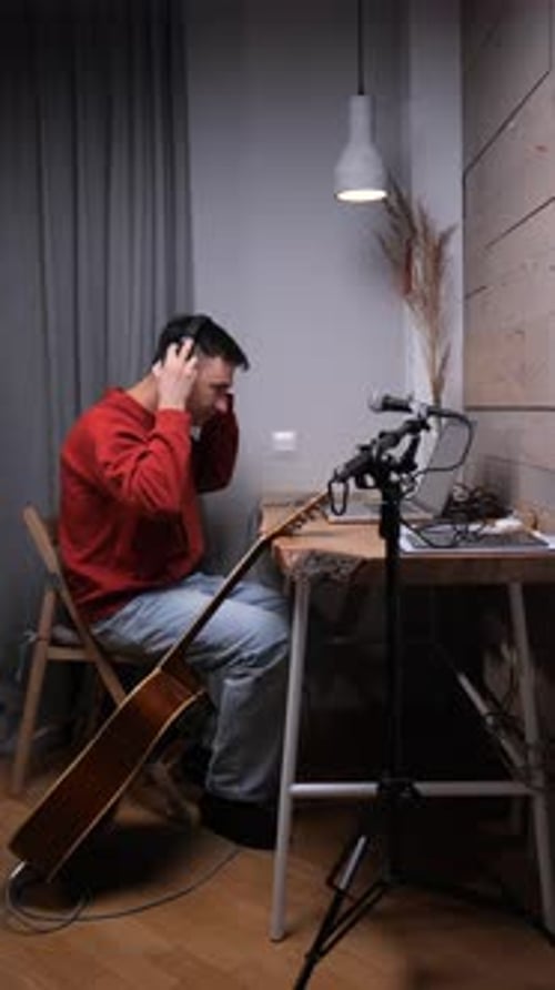 Vertical Video Man Wearing Headphones and Red Sweater Talking Into a Microphone Recording Audio for