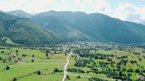 Clouds embracing majestic mountain peak over lush green valley