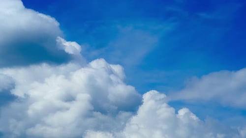 The bright sunlight of a summer morning illuminates the cloudy blue sky, timelapse