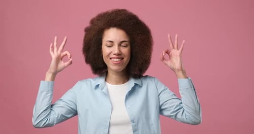 Smiling Woman Shows Okay Sign Against Pink Background