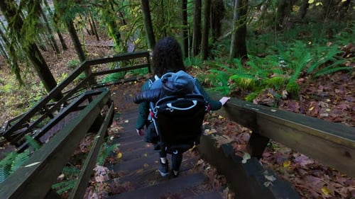 Mother Hiking Down Stairs with Baby in Backpack Carrier Fall Season Lynn Valley BC Canada