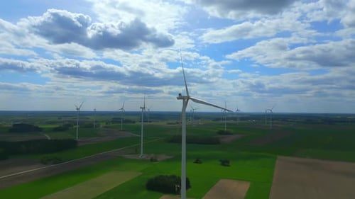 Cinematic view of wind turbines in action, as the camera circles around them, showcasing their