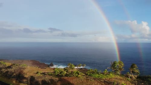 Two or double rainbow over the pacific ocean with cliffs in the foreground at sunset
