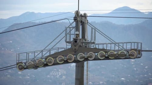 Support of ski lift with rotating rollers. Cable car passes by support tower. Cable car support