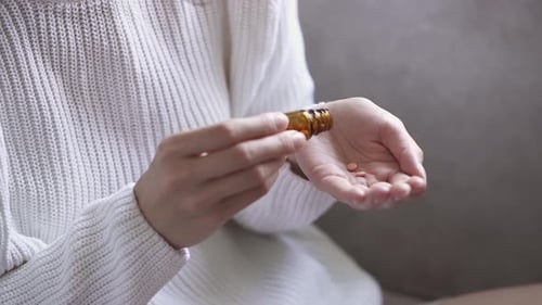 Woman Dispensing Pills From Bottle Into Hand