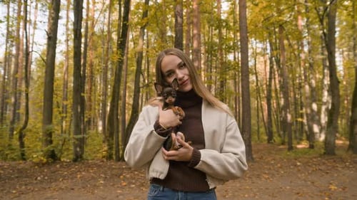 Portrait of Young Woman Holding Brown Dog Walking in Autumn Forest