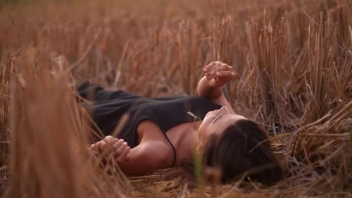 Young Playful Woman Lying on the Straw Field