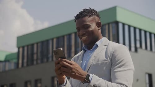 Smiling Man Using Smartphone in Urban Setting