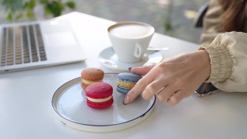 Person Working on a Laptop During the Break with Coffee and Macaroons