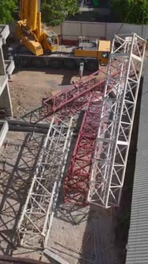 Vertical Video Skilled Workers Joining Large Crane Parts On A Construction Site Captured Aerially