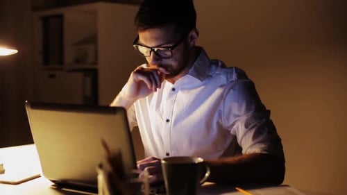 Man Working Late on Laptop at Desk