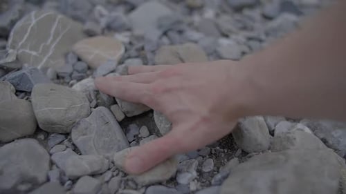 Person Touching and Feeling Stones Rocks Outdoors in Riverbed
