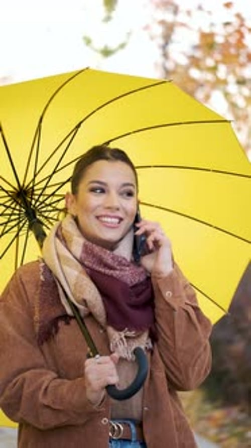 Smiling Woman with Yellow Umbrella Talking on Phone