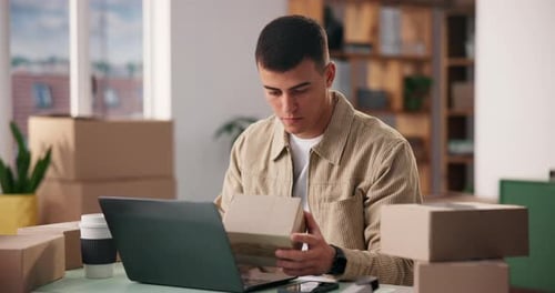 Young Man Working At Desk With Laptop and Boxes