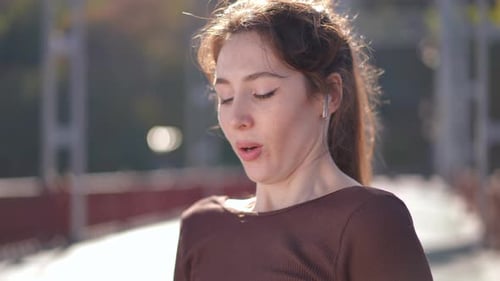 A Young Woman is Joyfully Enjoying Music While Outdoors on a Bright and Sunny Day