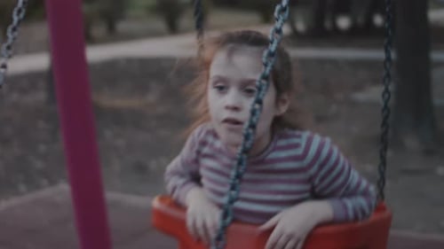8 Years Old Girl Having Fun on a Swing on the Playground