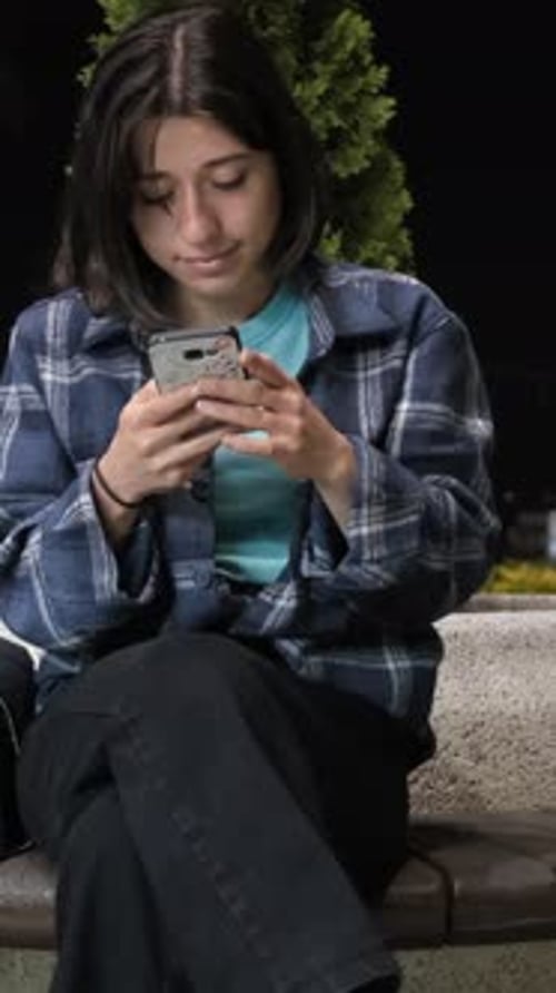 Woman Using Phone at Night in the City