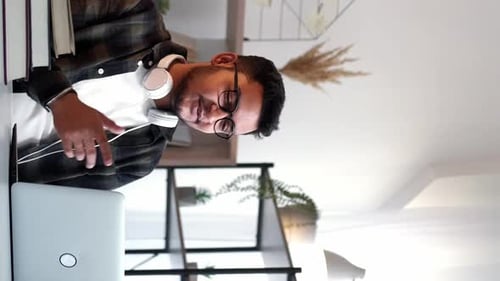 Young Adult with Laptop and Headphones at Desk