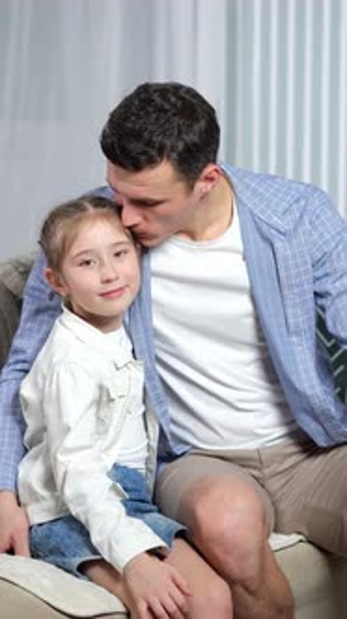 Young Man Cuddling with Child on Couch