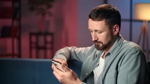 Pensive Casual Man Smartphone Chatting Scrolling Social Networks Night Dusk Lighting Home Interior