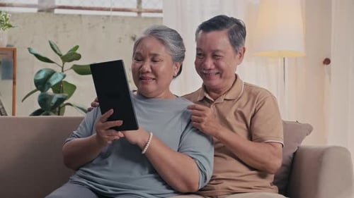 Senior Couple Uses Tablet Device on Sofa