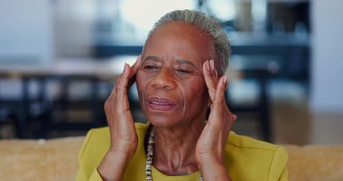 Stress, headache and senior black woman on a sofa with pain, problem or brain fog in her home