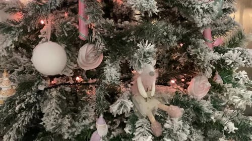 A close-up of a beautiful Christmas tree, decorated with sparkling lights, shiny ornaments, and colo