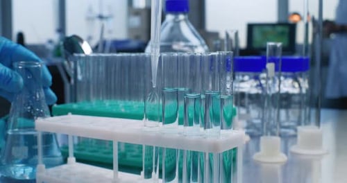 Scientist in Medical Laboratory Fills Test Tubes with Liquid of Developed Sample