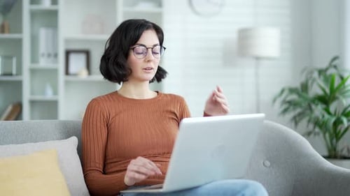 Überarbeitete junge Frau, die unter Augenbelastung und Kopfschmerzen leidet, während sie am Laptop sitzt