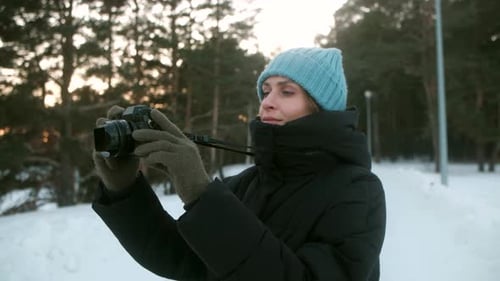A Young Woman Photographer Takes Pictures in a Winter Forest on Camera