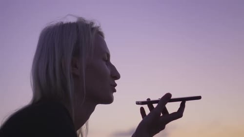 Woman dictates message using voice recognition on street on smartphone.