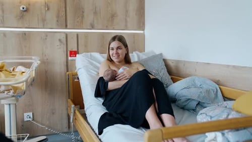 Modern pregnant hospital room. Lady with newborn baby in nursery ward.