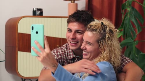 Affectionate Couple Taking Selfie Indoors with Mobile Phone