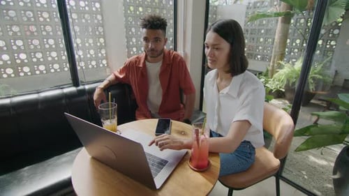 Colleagues Using Laptop during Meeting in Cafe