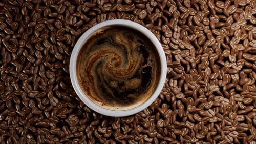 Top view of coffee cup and roasted beans.