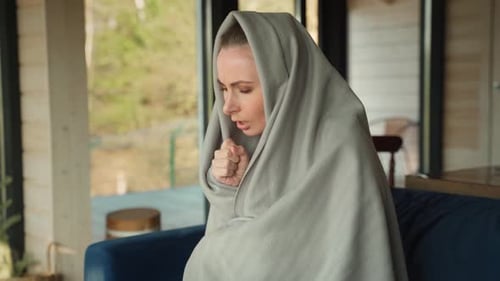 Young Woman with a Cold Coughs Sore Throat Covered with a Blanket