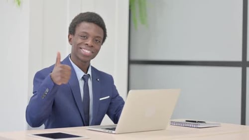 Man Giving Thumbs Up While Working on Laptop