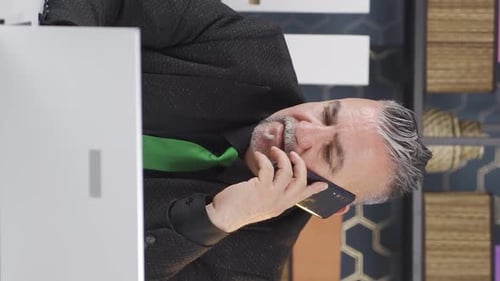 Man Talking on Phone Using Laptop in Office