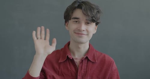 Young Man Waving Hello at the Camera