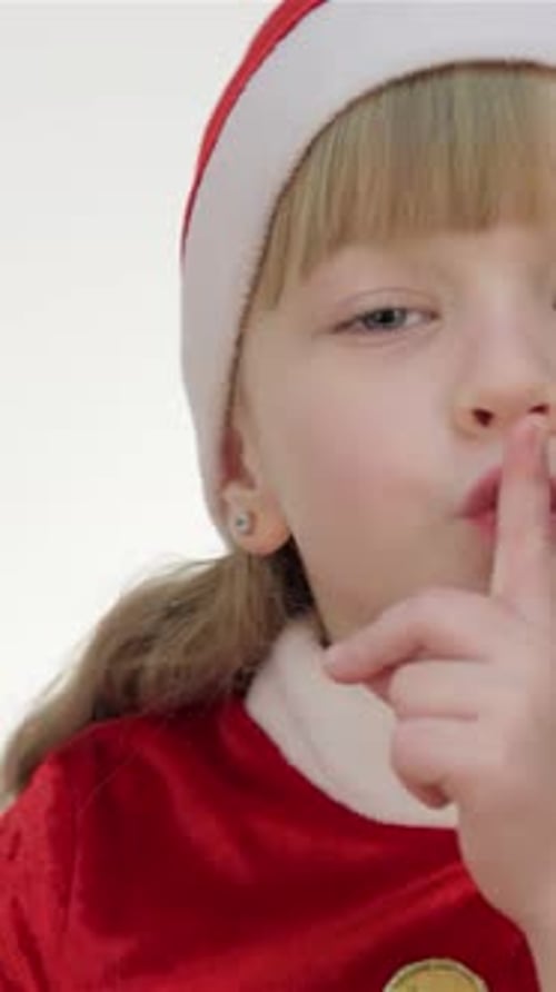 Girl in Santa Costume Shushes Finger to Lips