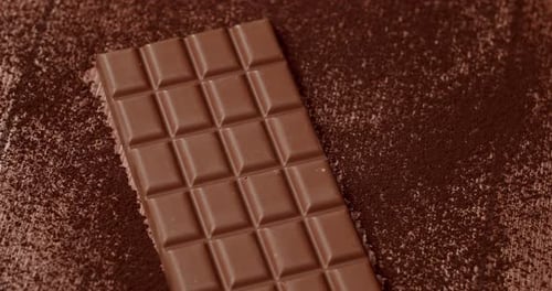 CloseUp Of Chocolate Bar On Cocoa Powder Background For Food Concepts