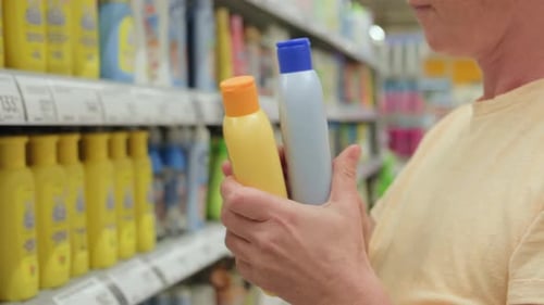 Female shopper takes goods from shelves in supermarket