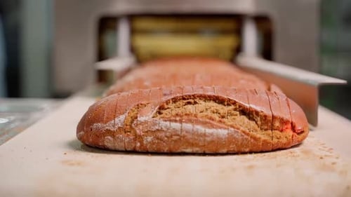 Brown Bread Loaves Being Sliced in Bakery