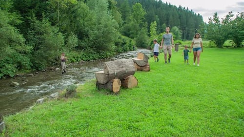 Young happy family enjoys walk in nature, boy looks at fisherman, Slovenia