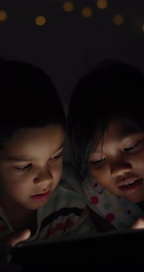 Two Children Watch Tablet Together at Night